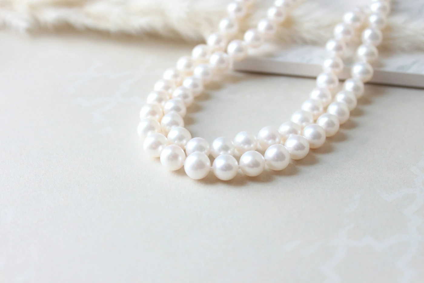 Double strand of white pearls on ivory fabric