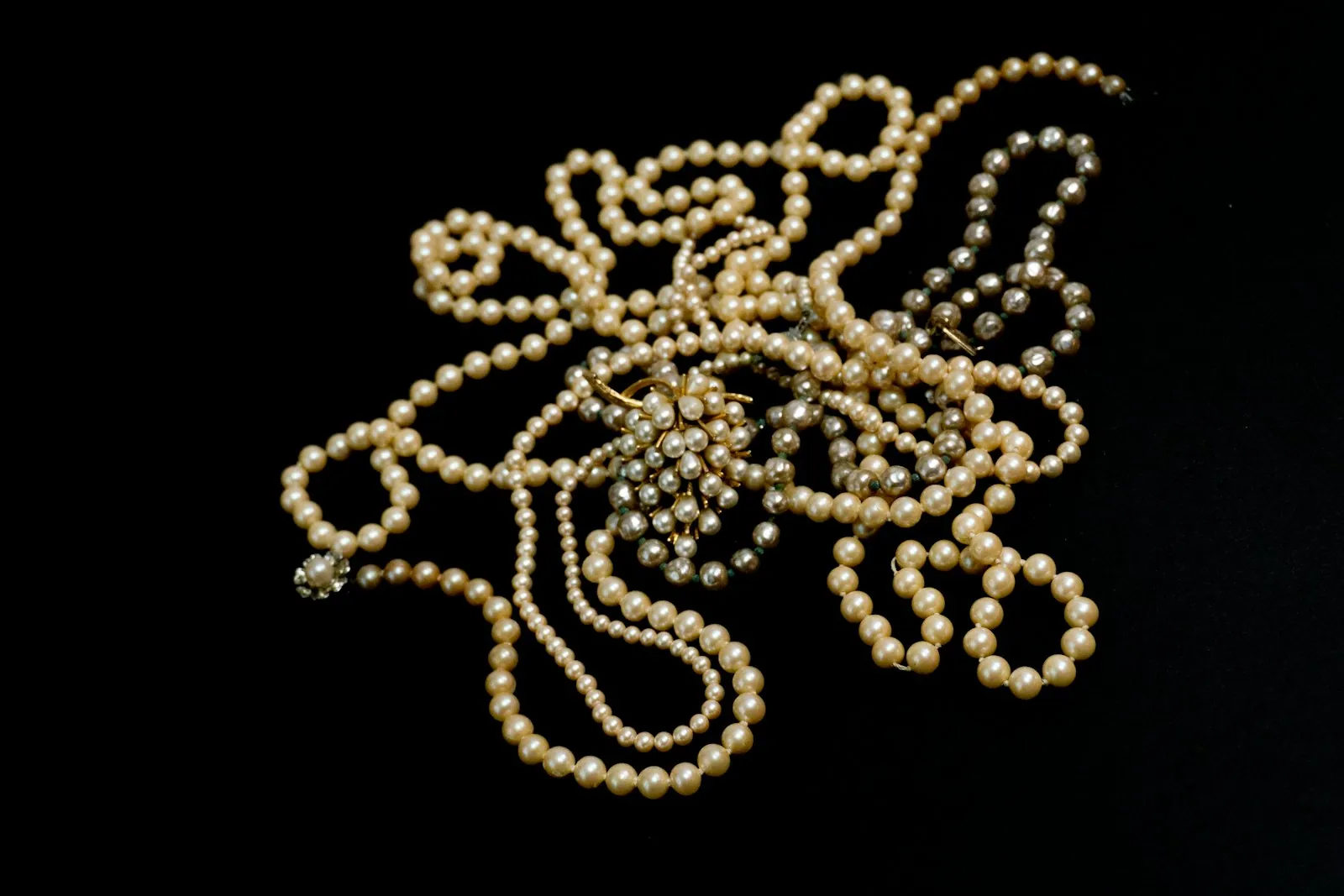 Loose pearl strands gathered on a black background