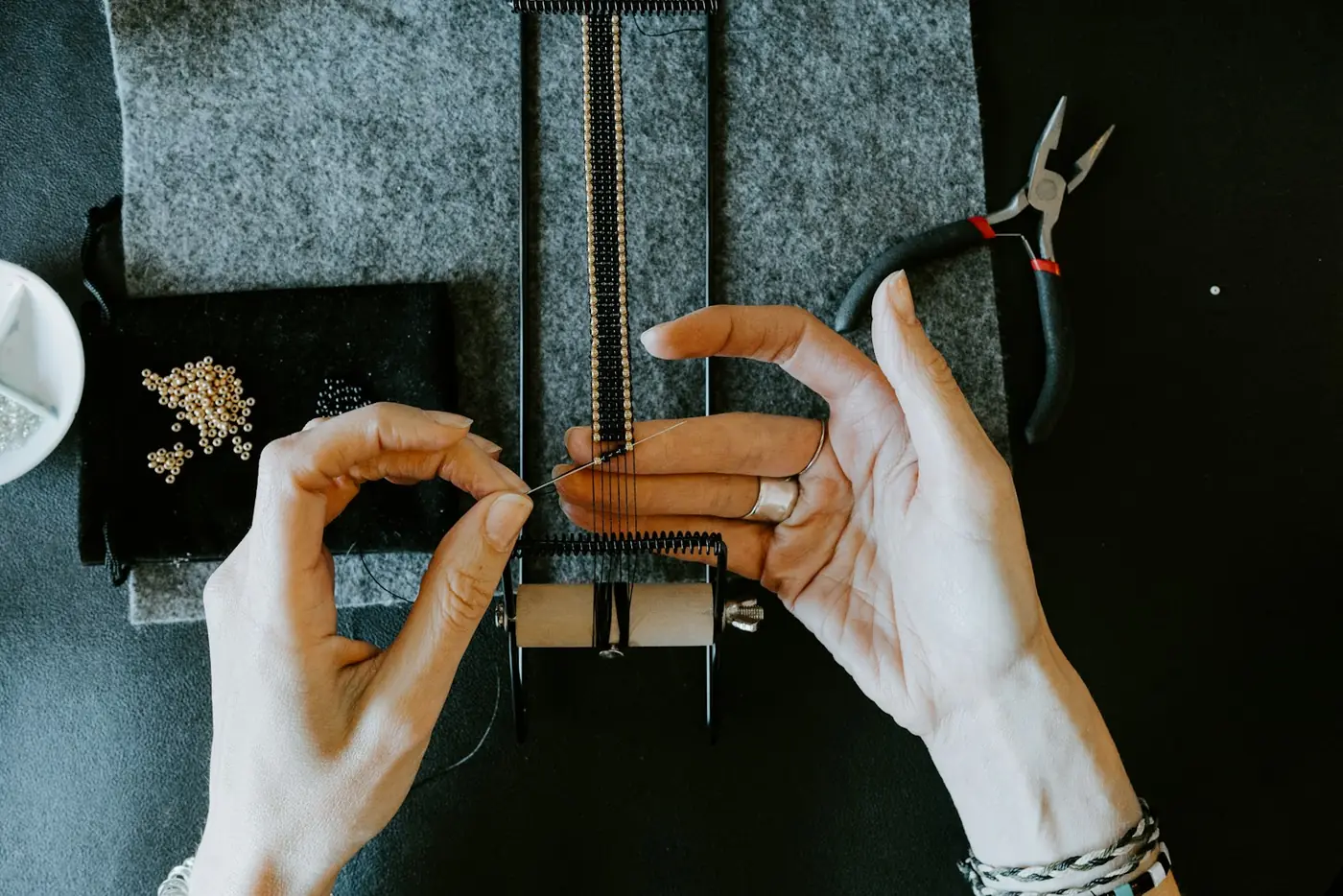 Jeweler working a piece at the bench with pliers