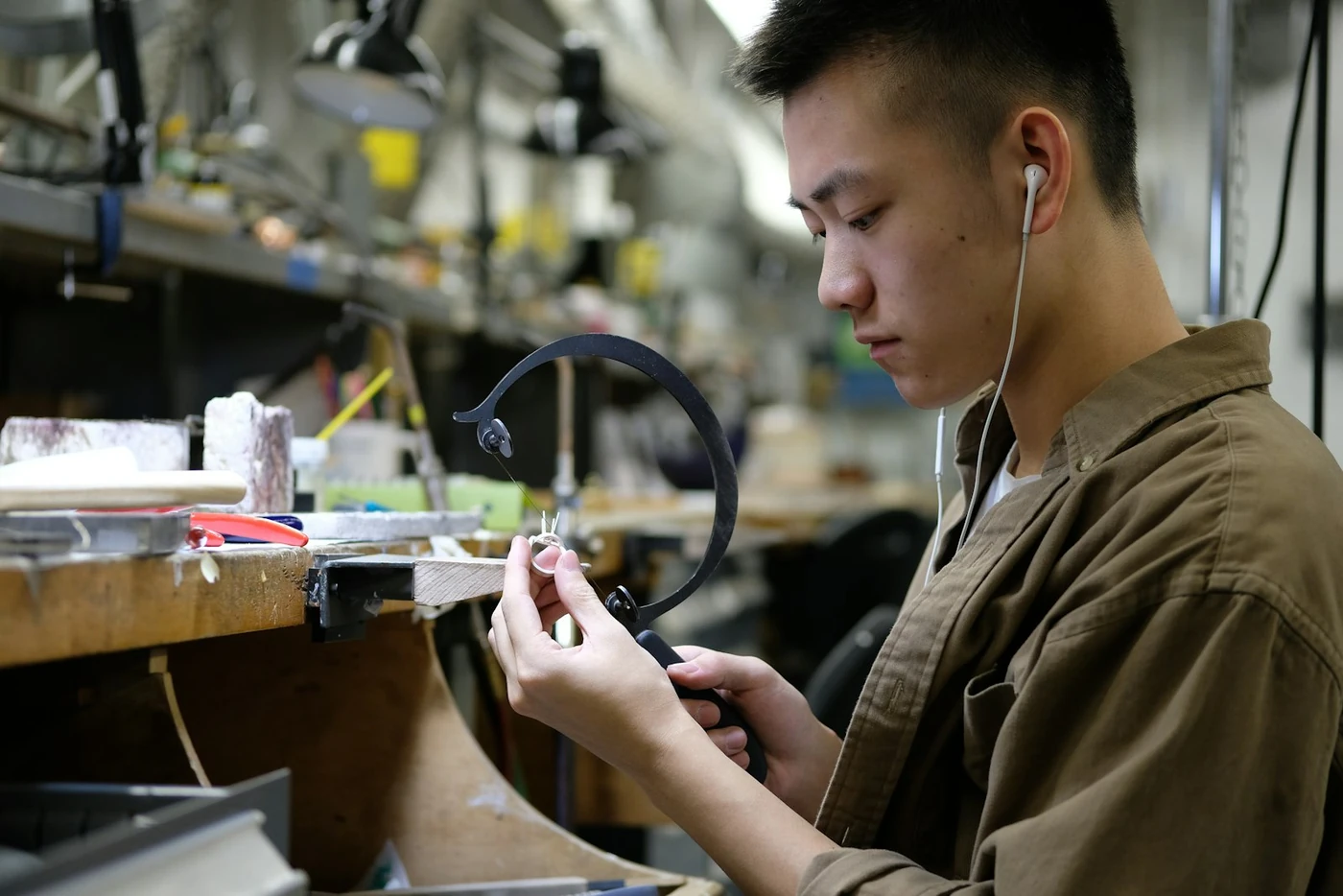 Jeweler inspecting a piece closely at a workshop bench