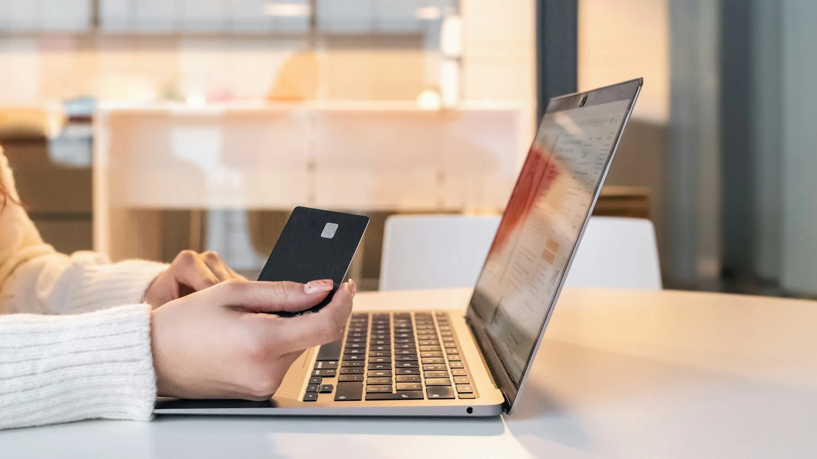 Shopper holding a card while ordering on a laptop