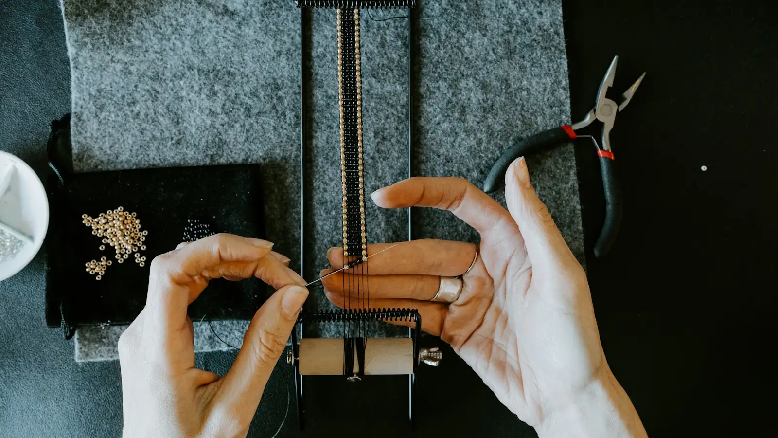 Hands assembling a piece of jewelry at a workbench