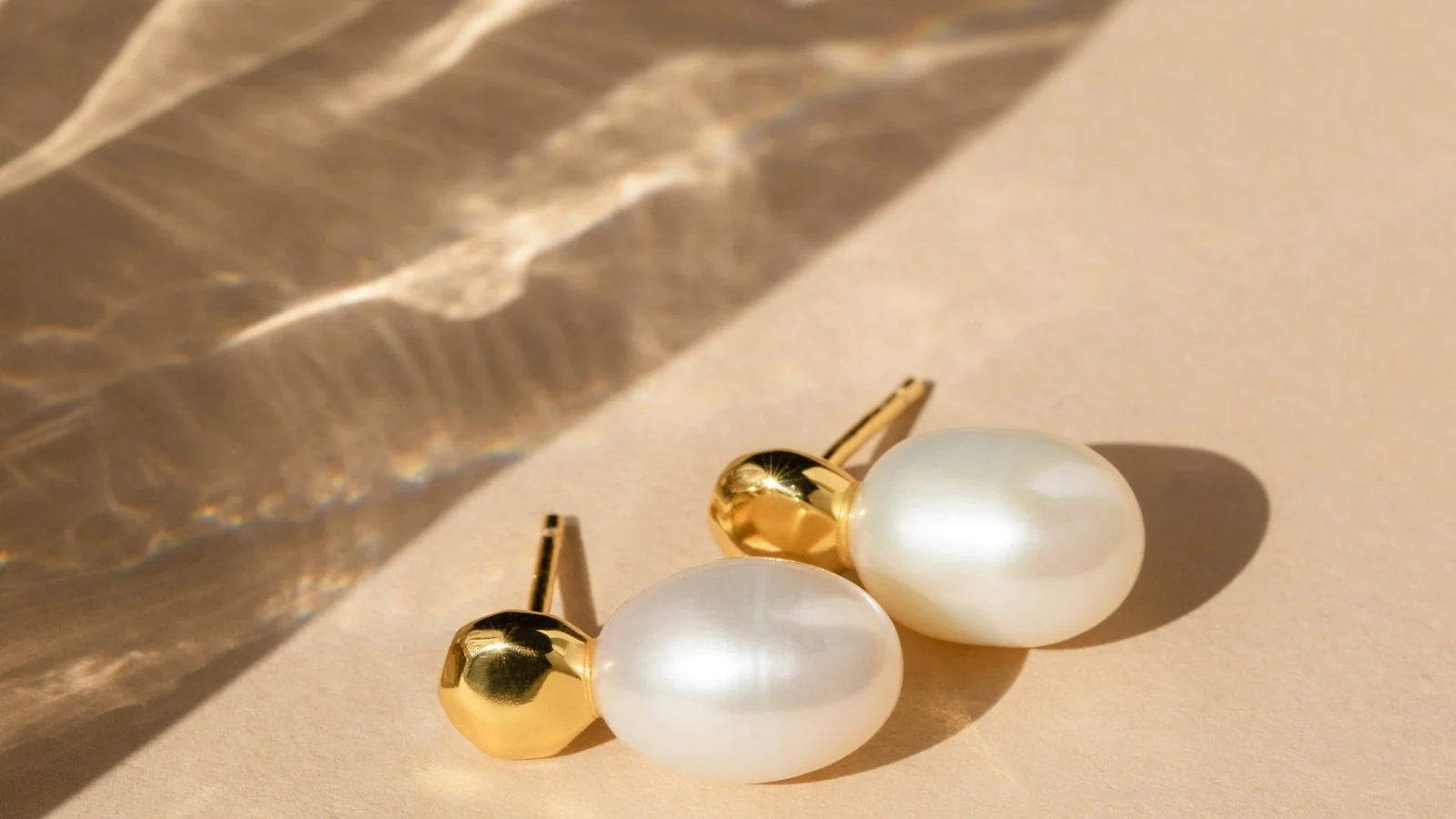 Pearl earrings with gold posts on a warm background